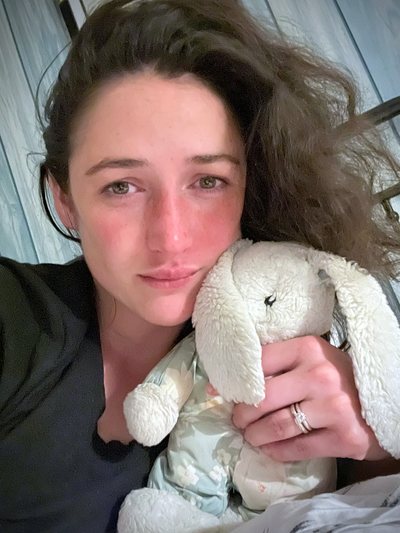 Elizabeth, late at night, holding a well-loved white stuffed rabbit against her cheek.